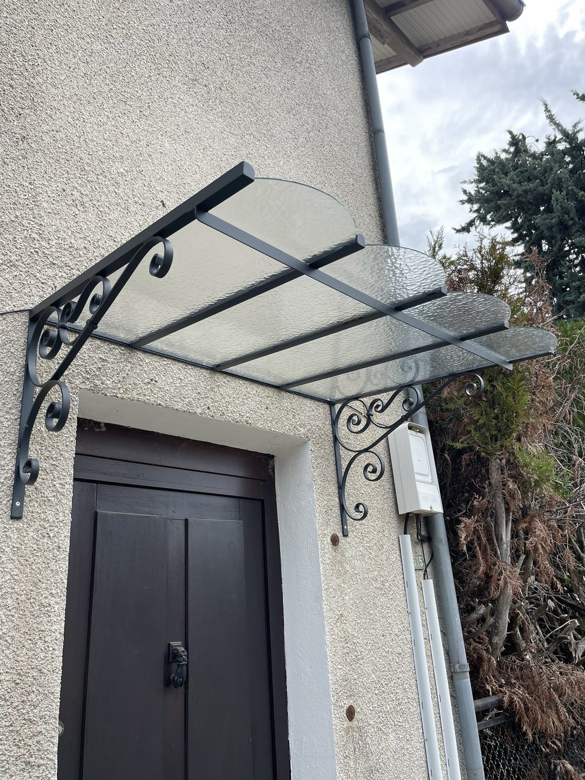 Marquise à volutes forgées au-dessus d'une porte d'entrée